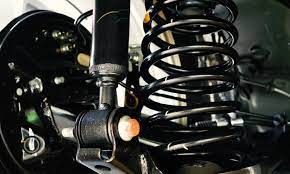 Close-up view of a car suspension system showing the coil spring, shock absorber, and surrounding mechanical parts.