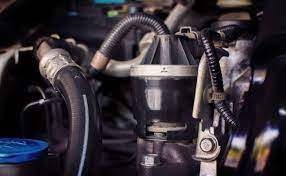 Close-up view of a car engine component showing hoses, clamps, and a fuel filter in the engine bay.