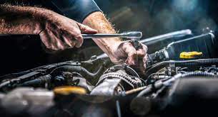 Mechanic using a wrench to repair or service a car engine, showcasing hands-on automotive maintenance and repair work.