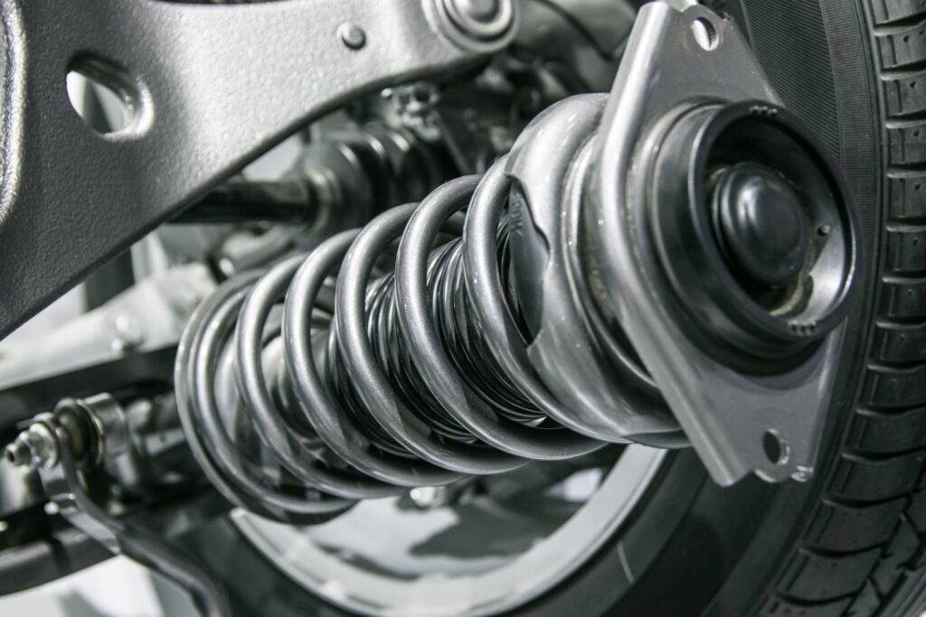 Close-up view of a car's coil spring and suspension system components mounted near the wheel for shock absorption.
