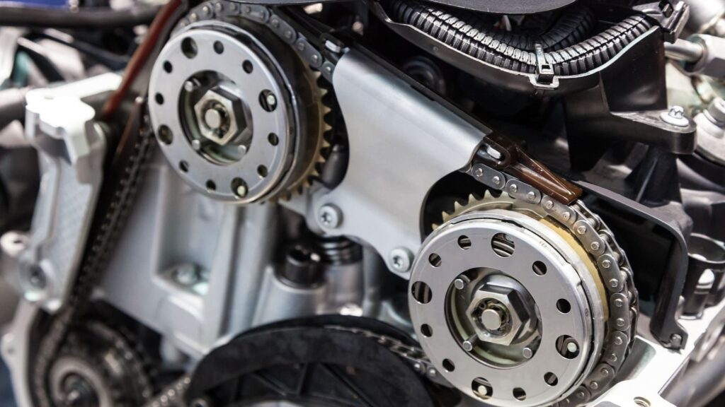Close-up view of a car engine timing chain and dual camshaft sprockets, showing detailed internal engine components.